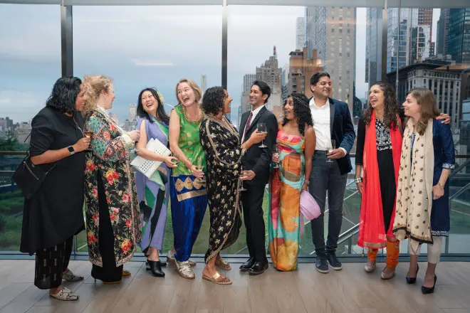A group of friends laughing together by a window overlooking the city.