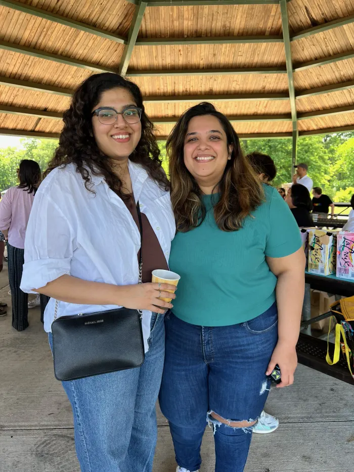 Two people smiling side by side under the picnic pavilion at the 2024 New Jersey picnic.