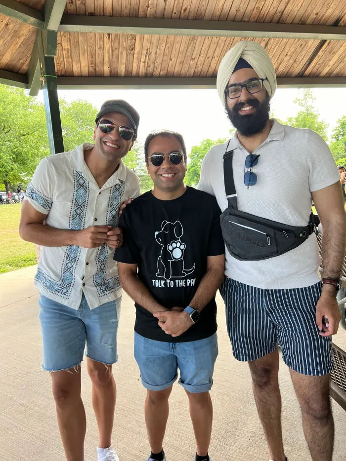 Three friends smiling together under the picnic pavilion at the 2024 New Jersey picnic.