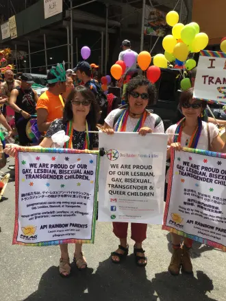 Parents marching at Pride with signs reading We are proud of our gay, lesbian, bisexual and transgender children.