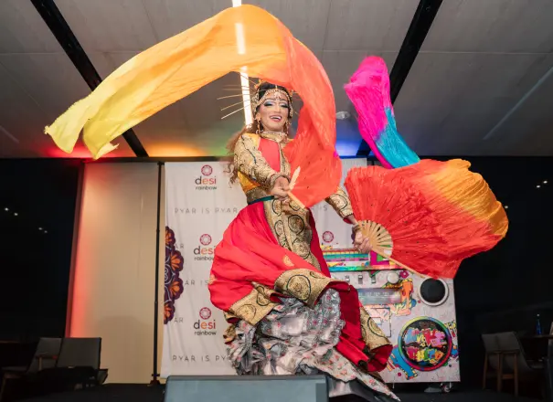 A dancer twirling long orange and pink silk fans on stage at Pyar is Pyar.