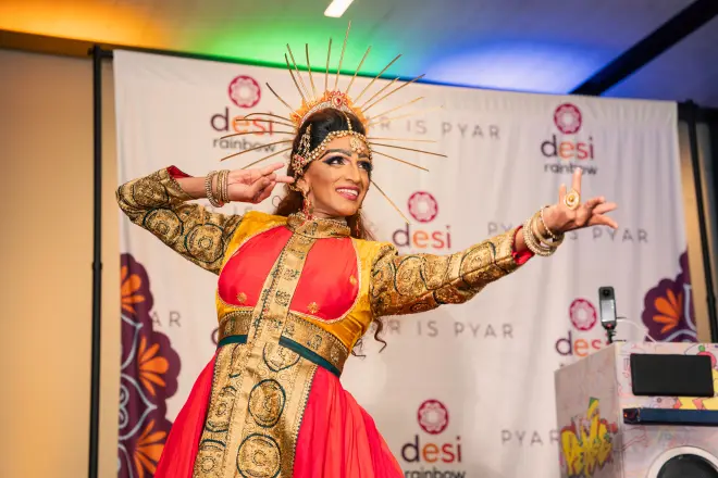 A classical Indian dancer in a red and gold costume and headdress performing at Pyar is Pyar.