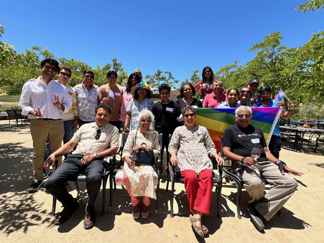 Desi Rainbow members of several generations at the 2025 Bay Area picnic, holding a rainbow flag and a transgender pride flag.