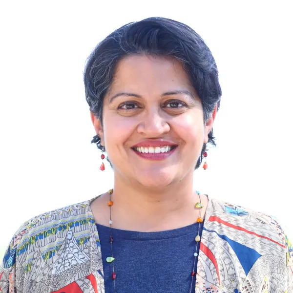 Portrait of Neeraja, smiling, in a patterned jacket.